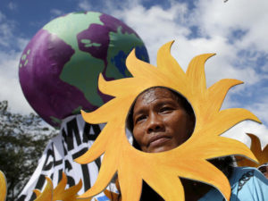 A Filipino environmental activist looks out from a "sun" cardboard cutout during a global protest action ahead of the 2015 Paris Climate Conference, known as the COP21 summit, in Quezon city, Metro Manila Philippines November 28, 2015. REUTERS/Erik De Castro - RTX1W72R
